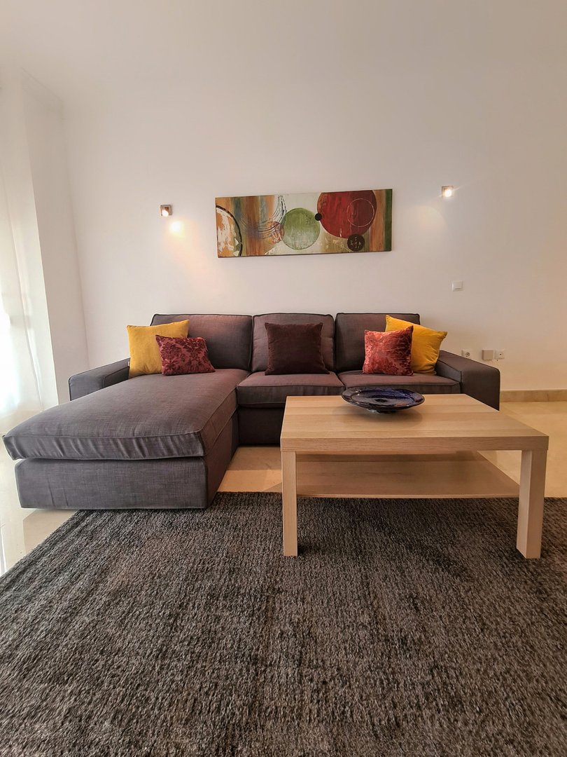 A modern sectional sofa in a living room with colorful throw pillows and a wooden coffee table.