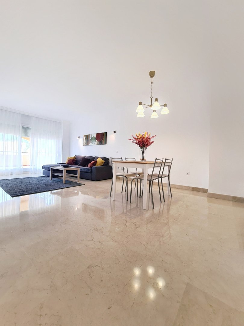 Spacious living and dining area with marble floors, modern furniture, a sofa, dining table, and bright natural light.