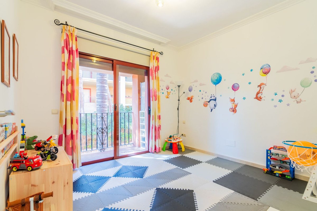 Playroom with colorful wall decals of animals and balloons, toys, and a balcony door leading outside.
