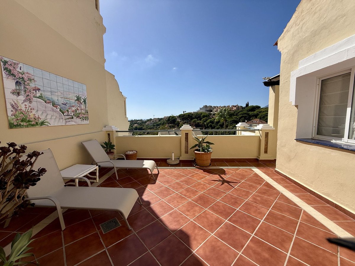 Terrace with lounge chairs and a scenic view of the coastline and sea under a clear blue sky.