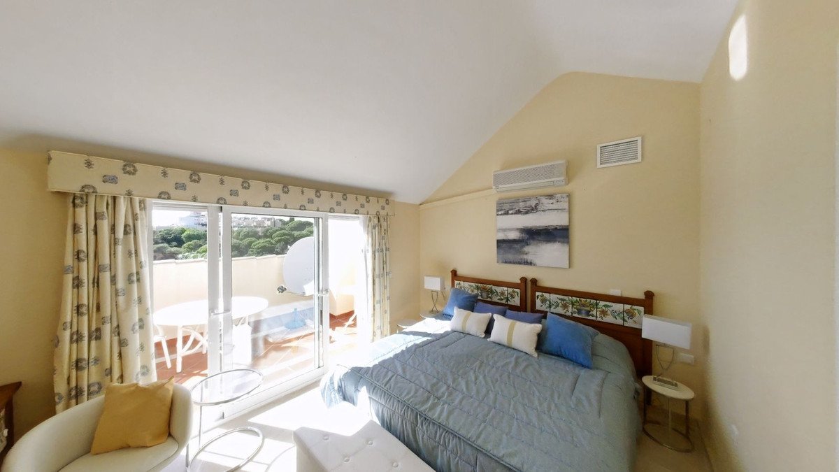 Bedroom with a large bed, blue and white bedding, and access to a balcony with sea views and outdoor seating.