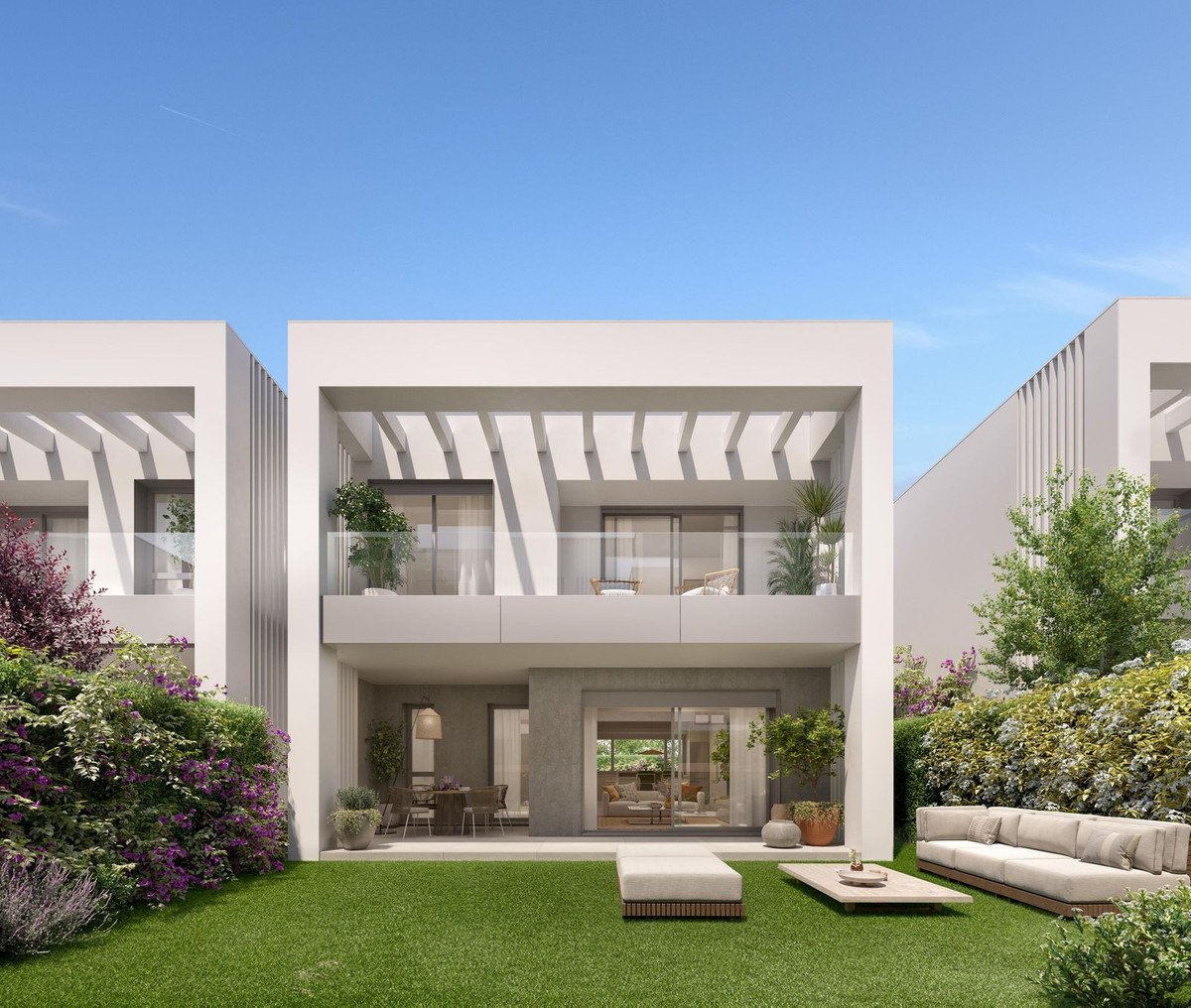 Modern white villa with balcony, glass doors, and lush green garden under blue sky.