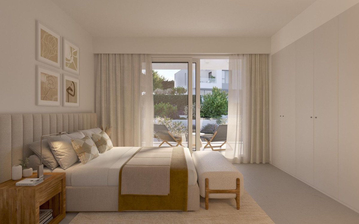 Modern bedroom with large bed, wooden nightstand, and balcony view through glass doors.