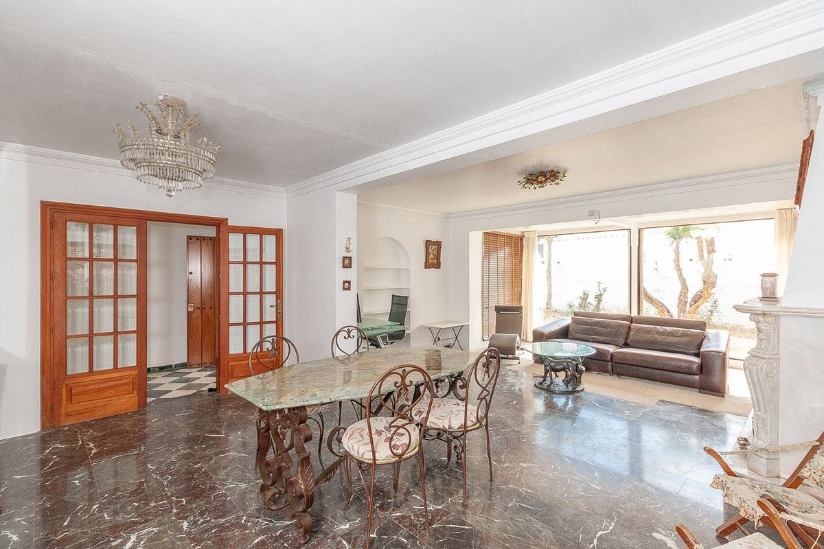 Spacious open-plan living and dining area with marble floors, large windows, a chandelier, and elegant furniture.