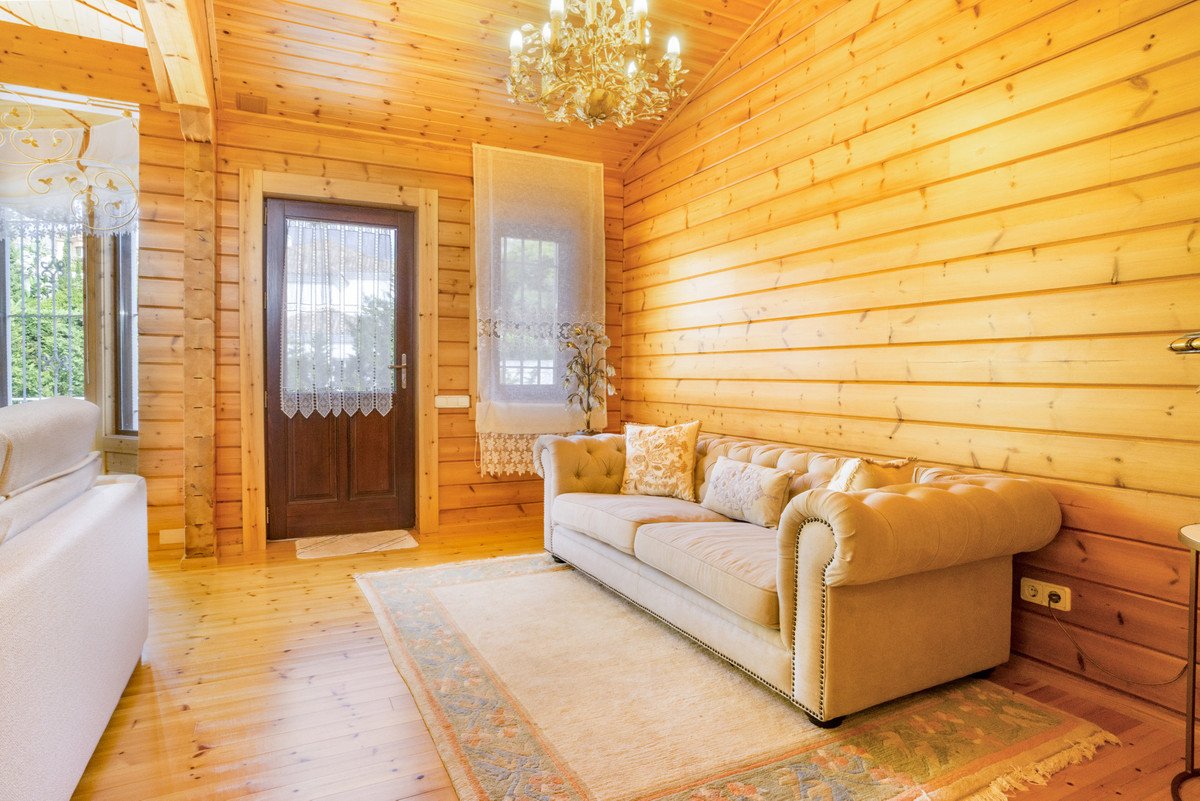 Wooden living room with chandelier, sofa, and natural light