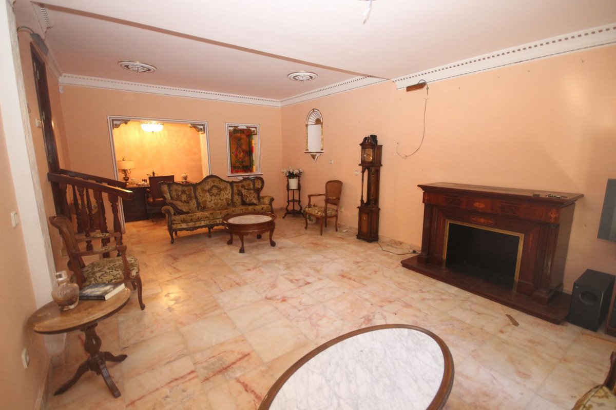 Spacious living room with a fireplace, antique sofa, grandfather clock, and marble floors.