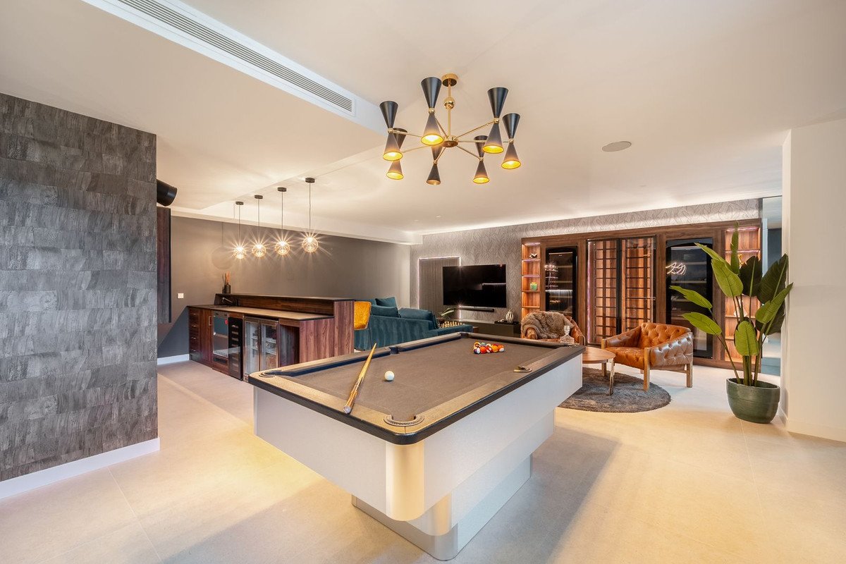 Modern lounge with a pool table, bar, wine cellar, TV, and comfortable seating, perfect for entertaining.