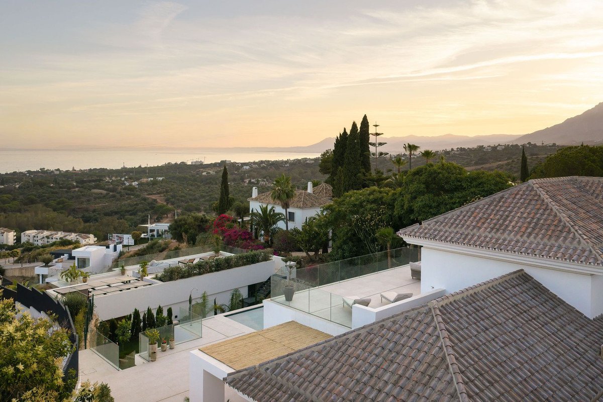 Spacious luxury villa with multiple terraces and stunning sea and mountain views during sunset.