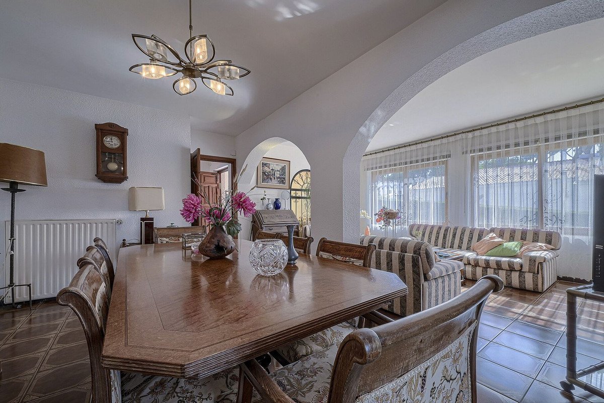 Dining and living room with arched window, striped sofa, and wooden table