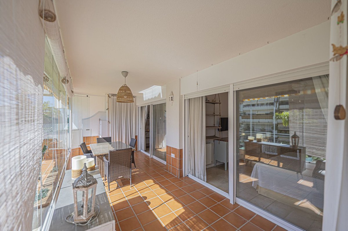 Glazed terrace with dining table and chairs, overlooking an urban view from the bedroom.
