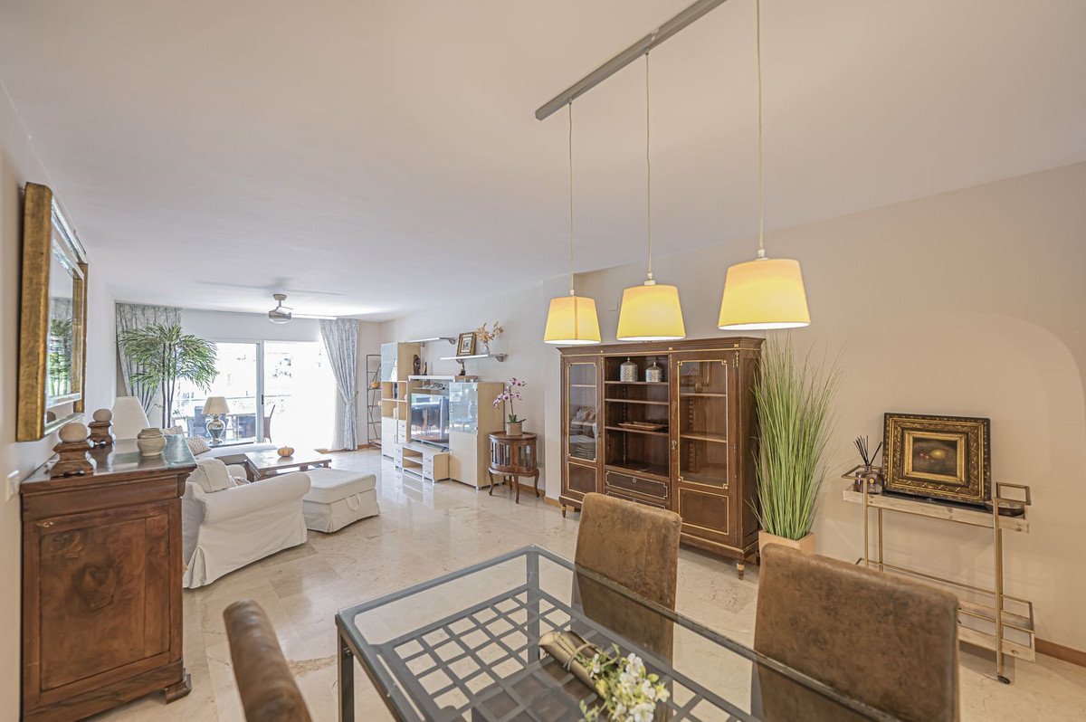 Bright and spacious living and dining room with large windows, comfortable furniture, and decorative cabinets.