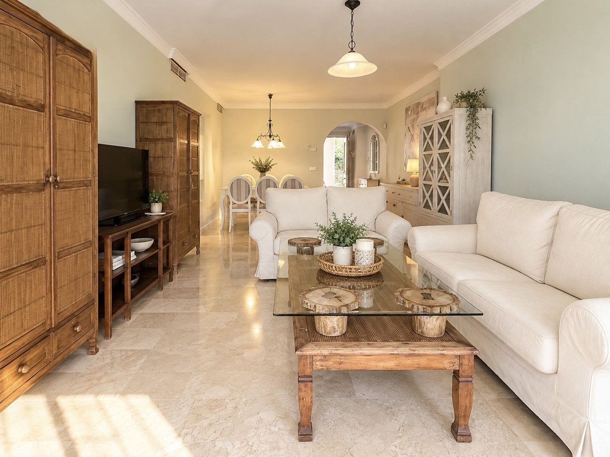 Spacious living room with white sofas, wooden furniture, and a glass coffee table.