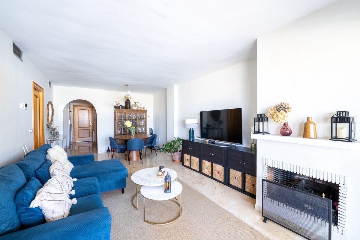 Living room with blue sofa, fireplace, and dining area in background