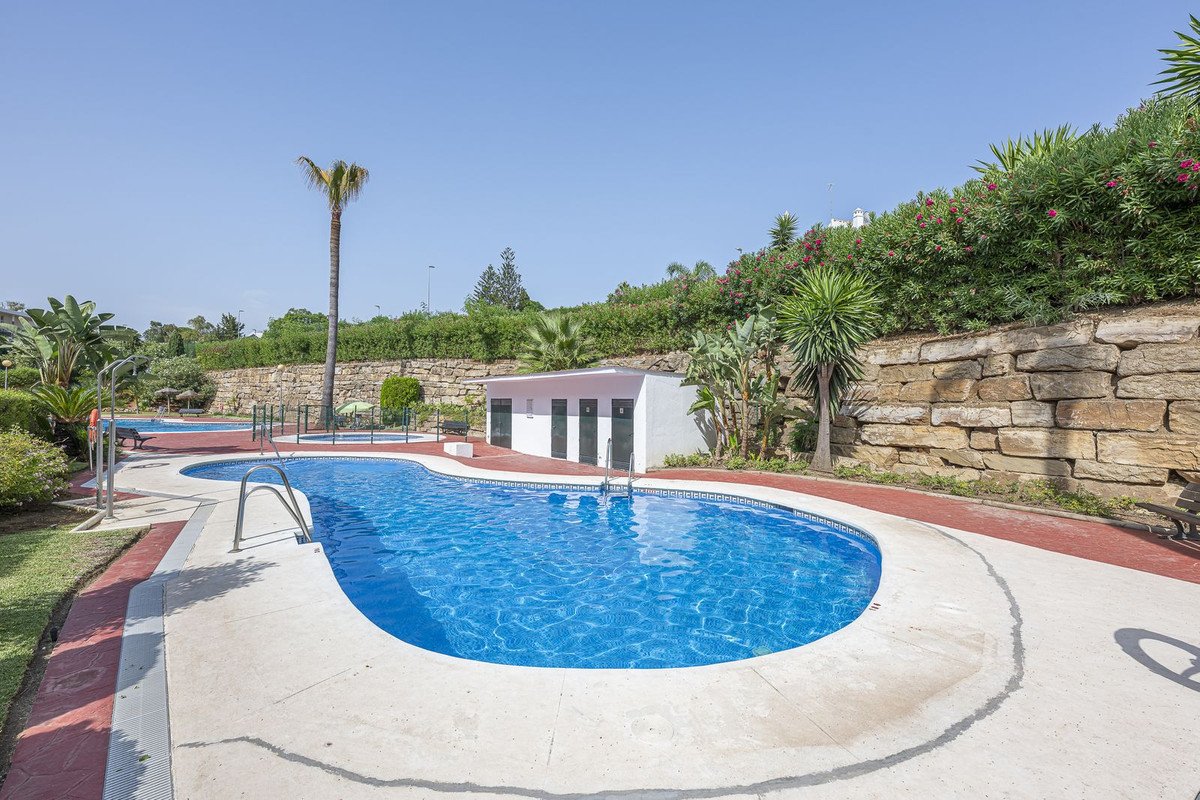 A beautiful outdoor swimming pool with clear blue water, surrounded by lush greenery and a stone wall. Perfect for relaxation.