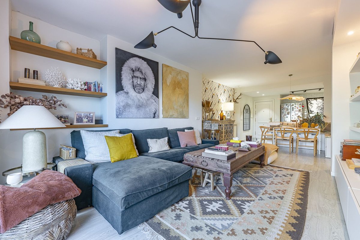 A spacious living room with a large sectional sofa, a decorative coffee table, and an adjacent dining area visible in the background.
