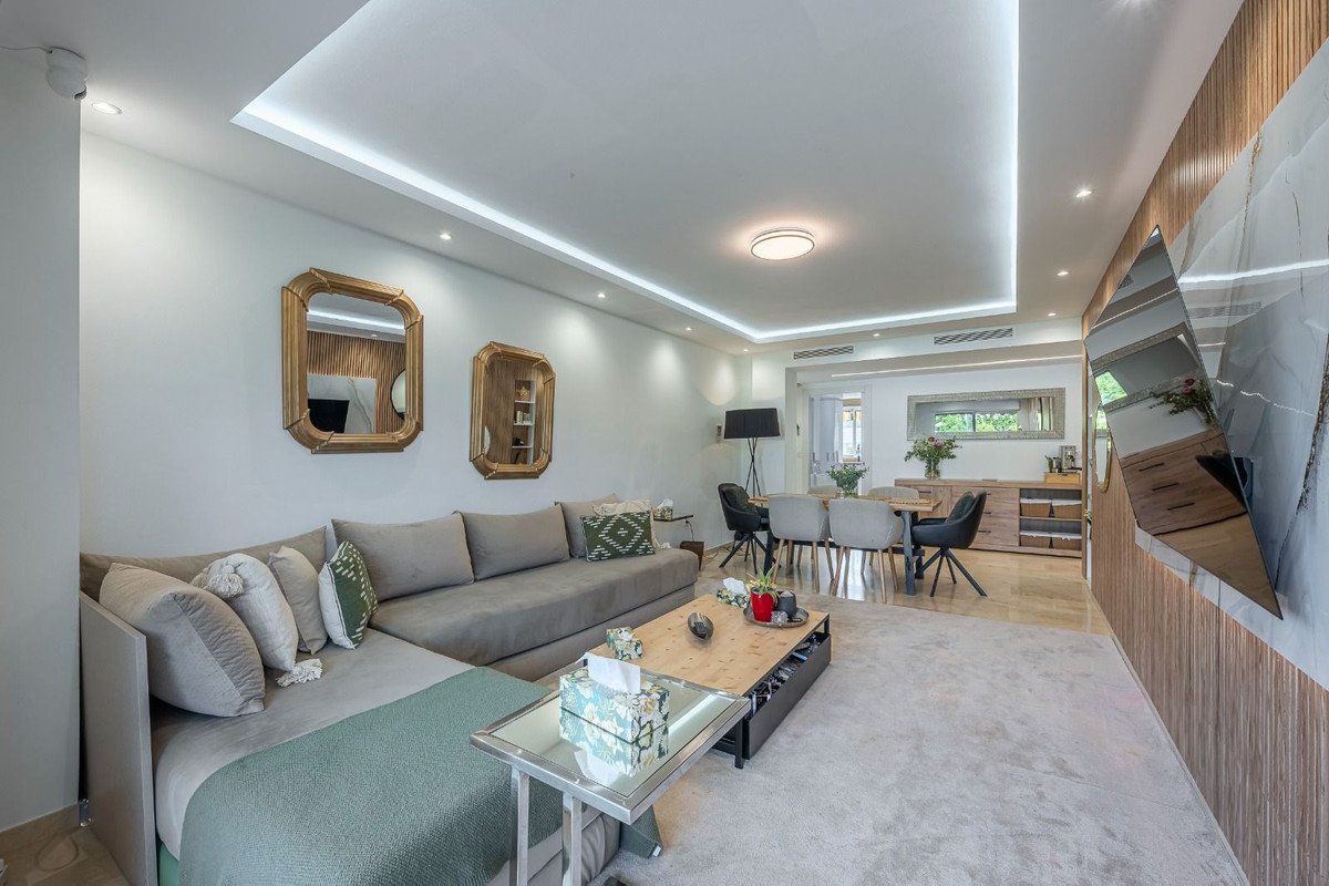Modern living room with grey sofa, coffee table, and open-plan dining area