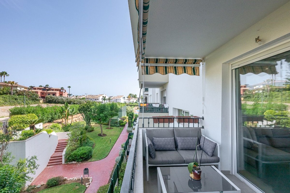 Balcony with grey seating, table, and garden view under awning