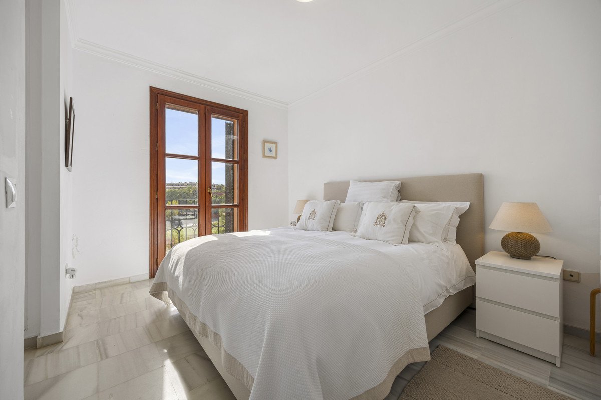 Bright bedroom with large bed, bedside tables, and garden view through wooden doors