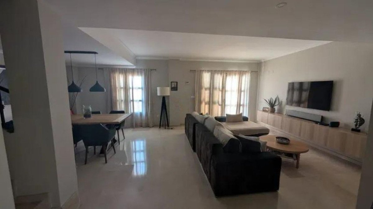 Spacious open-plan living and dining area with modern furniture, a large sofa, dining table, and TV console.