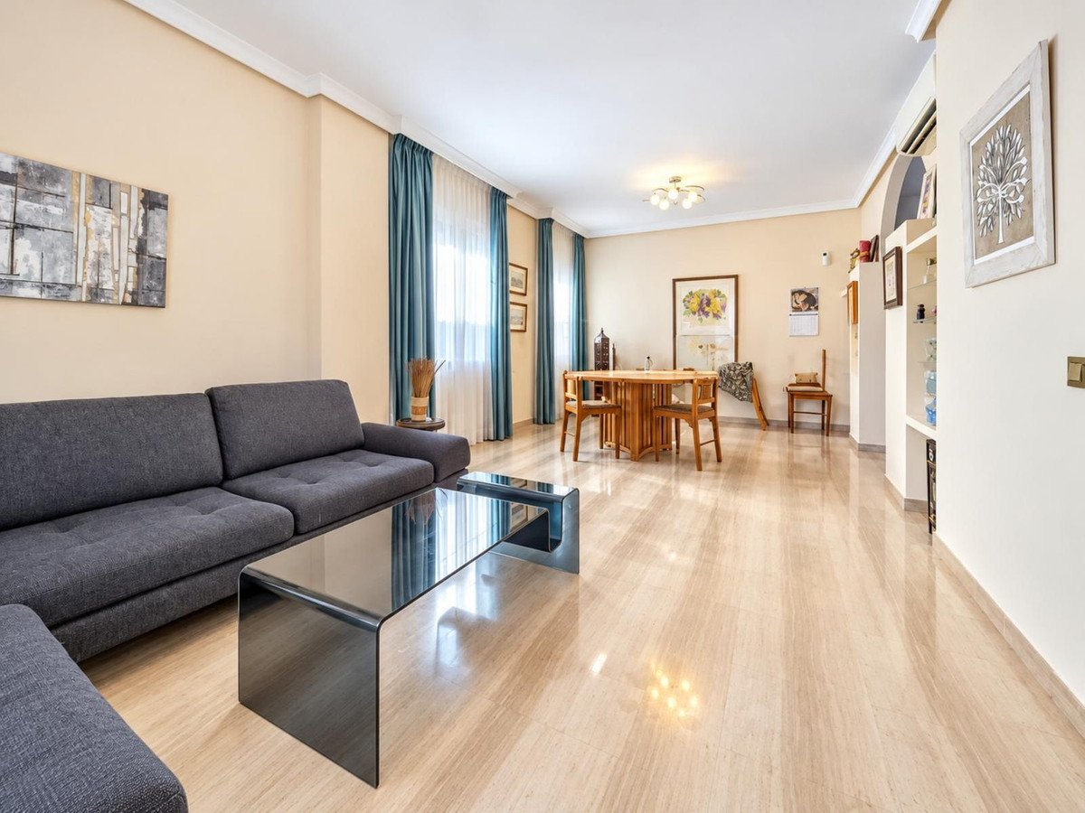 Spacious living and dining area with a large grey sofa, glass coffee table, and wooden dining set.