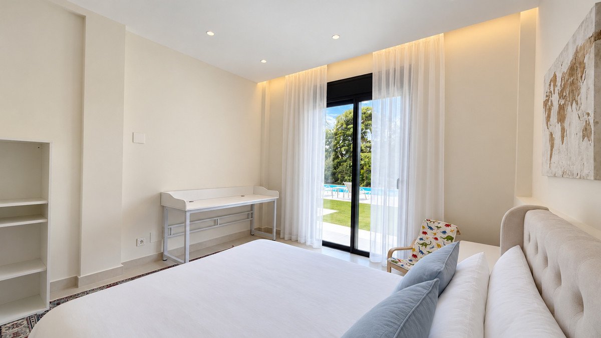 Spacious bedroom with pool view, large window, and built-in desk