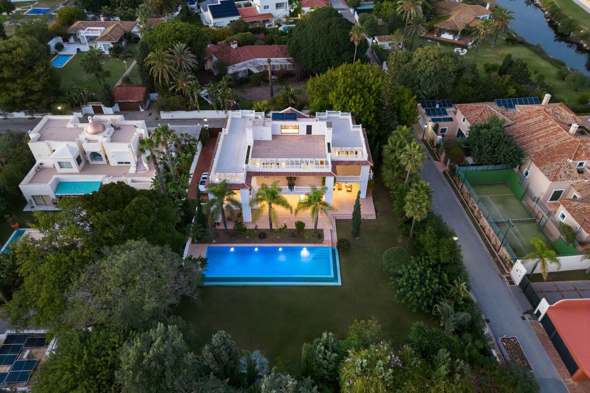 Aerial view of a luxury villa with a swimming pool and surrounding greenery