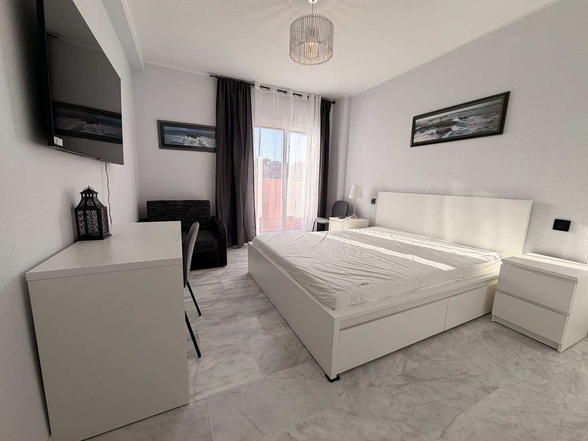 Modern bedroom with a large double bed, desk, television, and balcony access with a view.