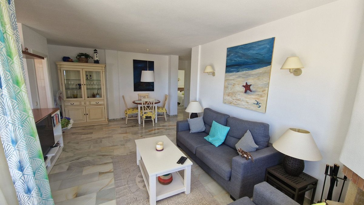 Spacious living room with gray sofa, dining table, and beach-themed artwork.