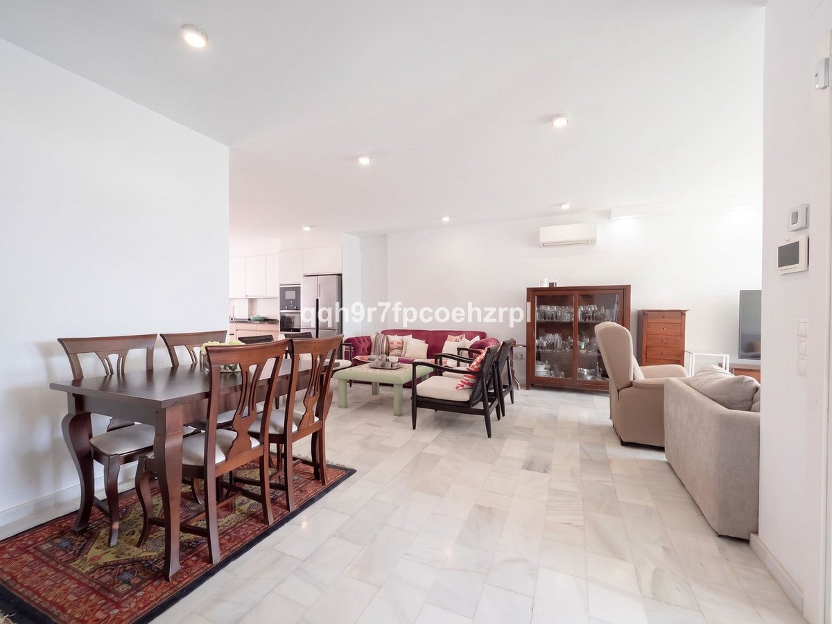 Spacious dining and living area with marble floors, comfortable seating, and a wooden dining table.