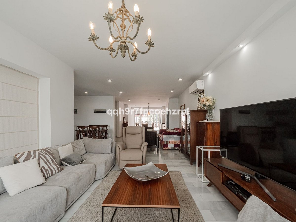 Spacious living room with a large sofa and coffee table, leading to a dining area with a wooden table and chairs.