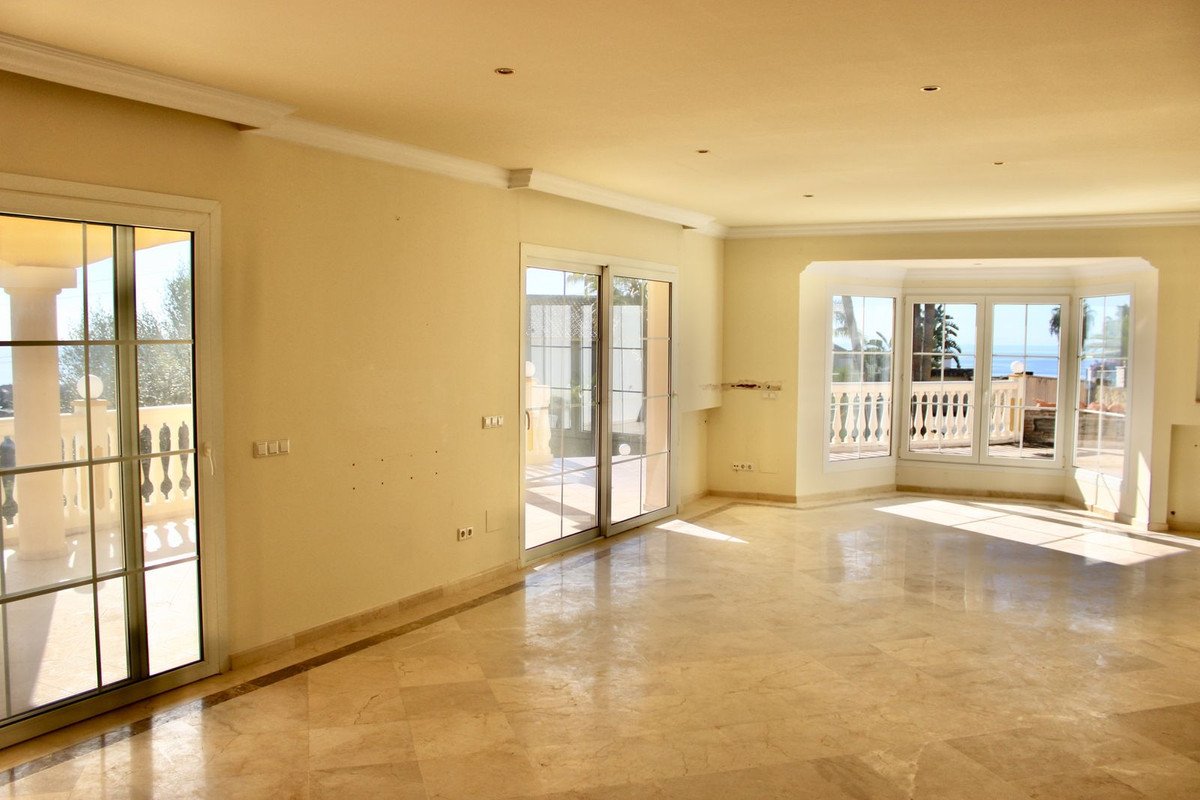 Spacious living room with marble floors, large windows, and balcony views of the sea.