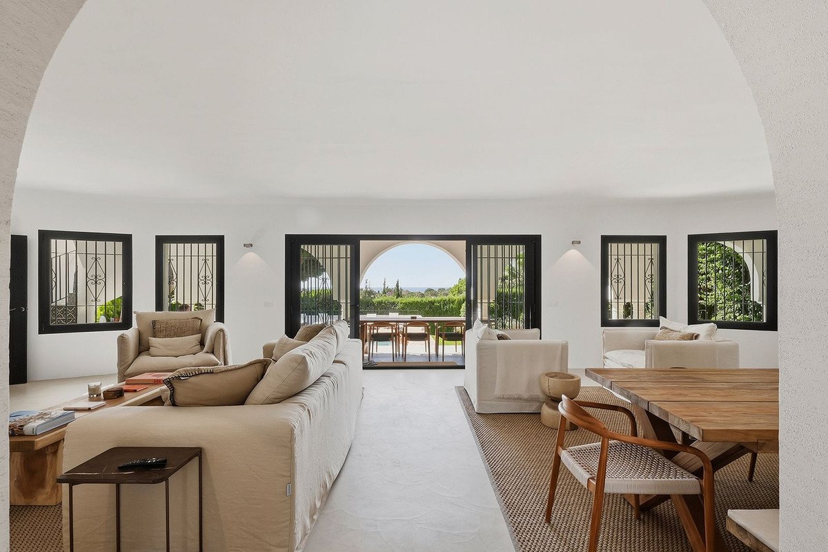 Spacious living room with comfortable sofas, dining area, and large sliding doors opening to a terrace with a sea view.