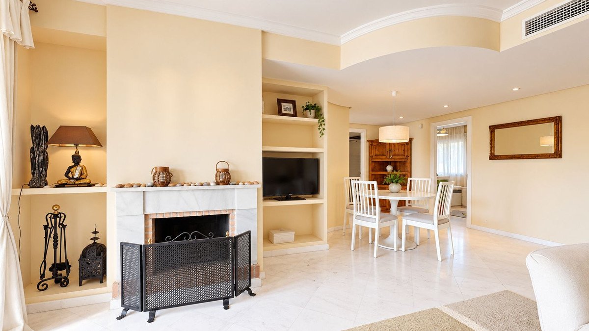 A bright living and dining room with a fireplace, built-in shelves, a TV, and a dining table with chairs.