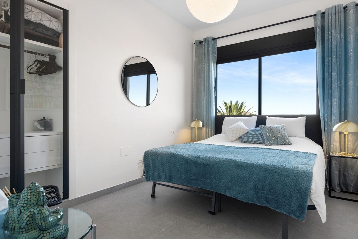Modern bedroom with king bed, blue accents, and ocean view through large windows.