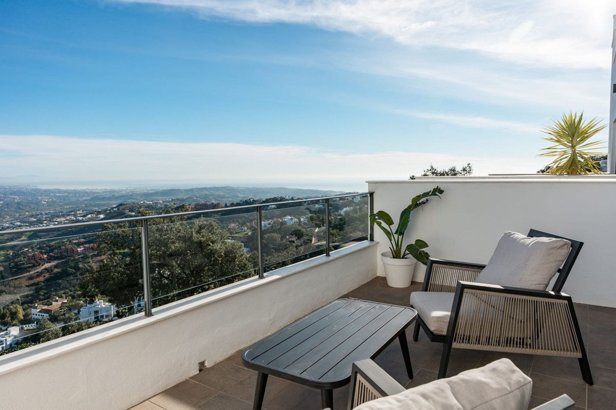 Modern balcony with seating area and a stunning panoramic view of the town and the sea on a clear day.