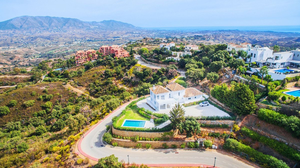 White villa with swimming pool and terrace overlooking the sea and mountains on a sunny day.