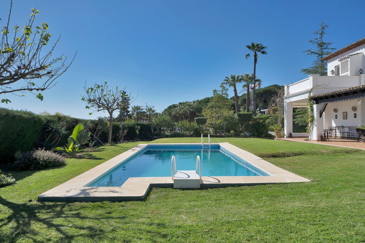 Villa backyard with swimming pool, green lawn, and outdoor patio area