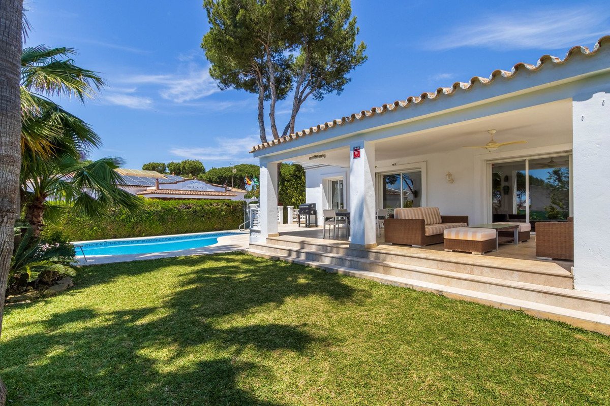 Modern villa with a private swimming pool, covered patio with outdoor seating and dining areas, sunny day.