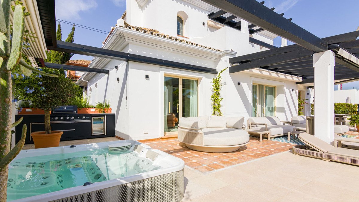 Luxury terrace with hot tub, outdoor kitchen, lounge seating, and pergolas, perfect for outdoor entertaining.