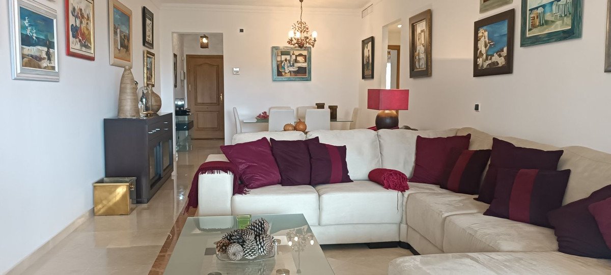 A bright living and dining room with a large sectional sofa, decorative pillows, and artwork on the walls.