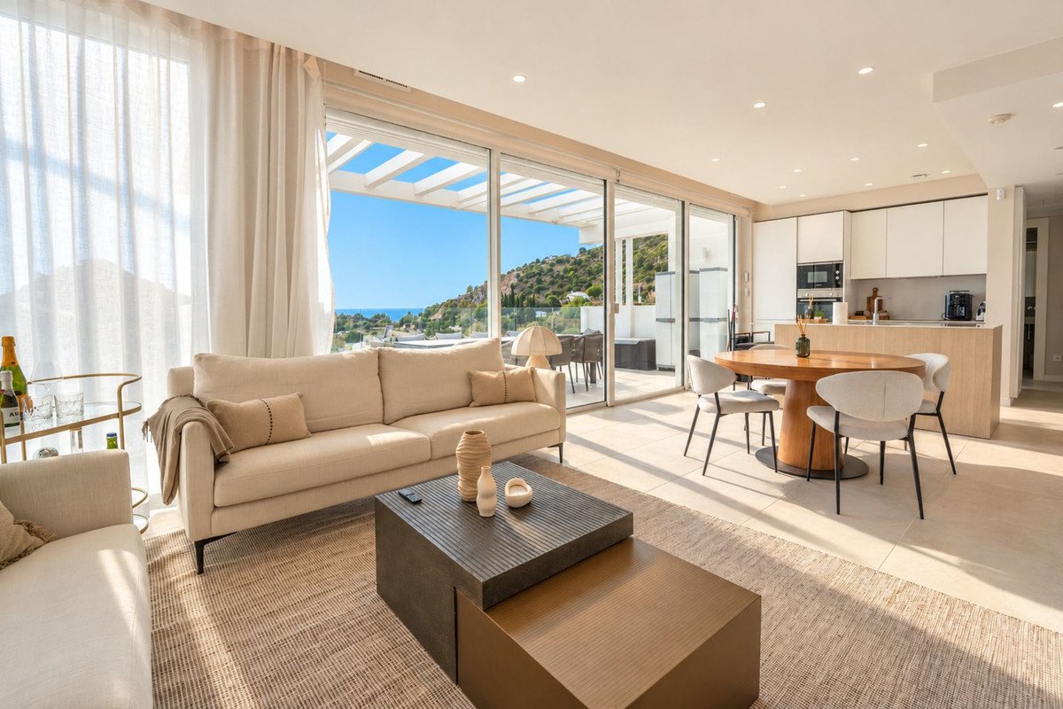 Modern living room with sea view, sofa, dining table, and open kitchen