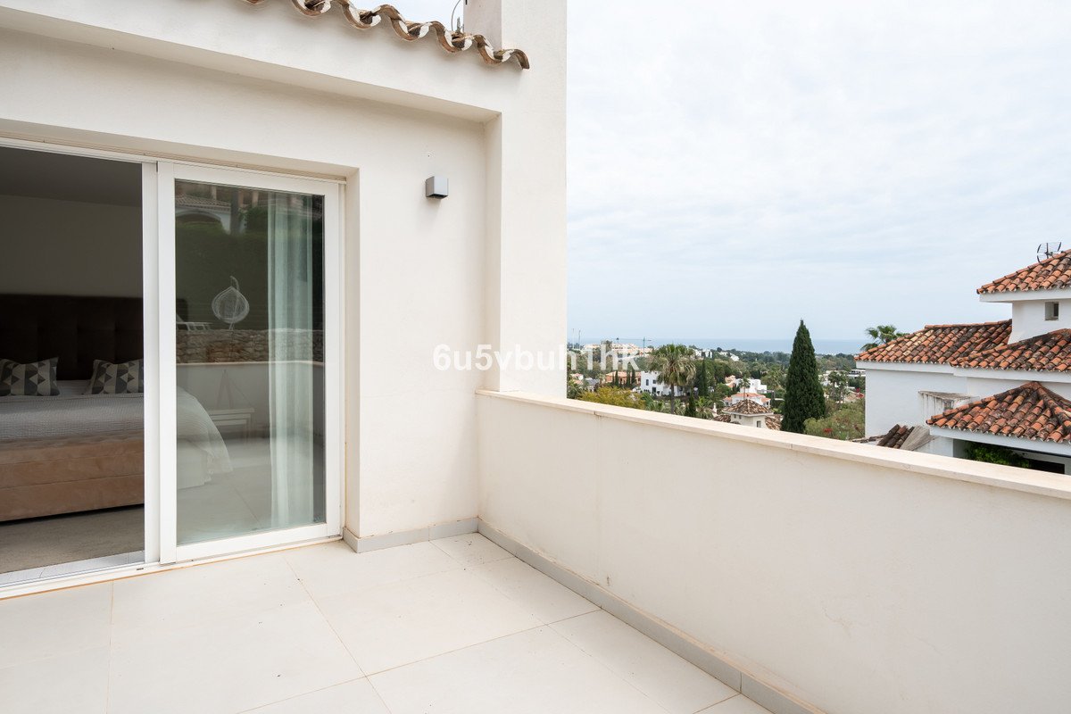 Spacious balcony with sea and town views, accessible from a bedroom with a large sliding glass door.
