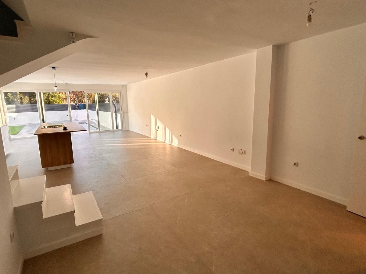 Spacious open-plan living and kitchen area with large windows overlooking a garden and modern island.