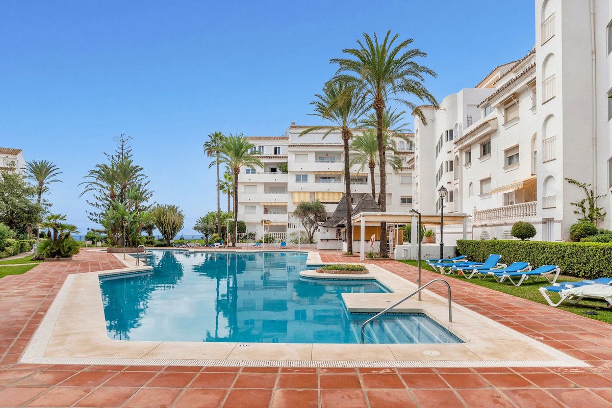 Swimming pool at apartment complex with palm trees and lounge chairs