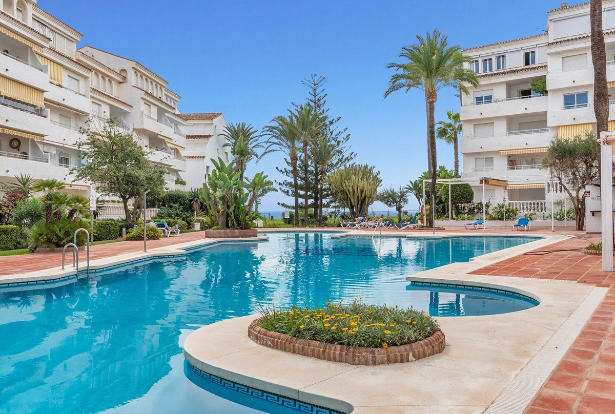 Swimming pool at an apartment complex with palm trees and clear blue sky