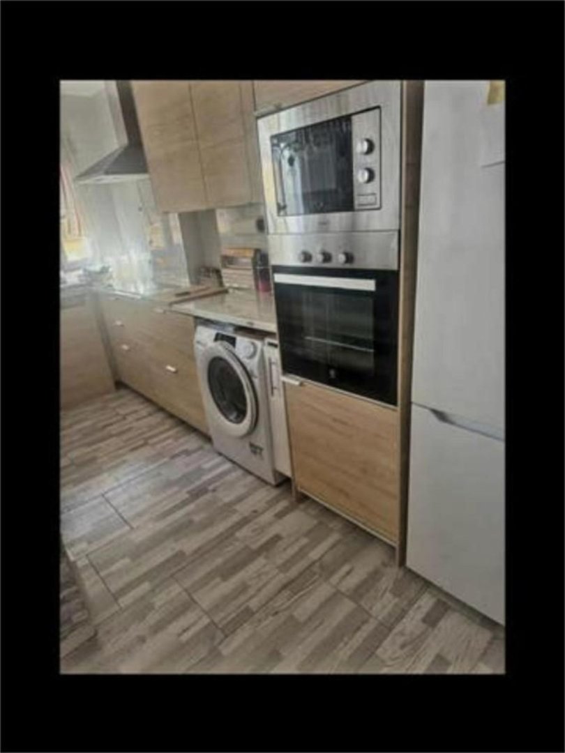 Modern kitchen with integrated oven, microwave, washing machine, and refrigerator. cream cabinets. Features modern tiling and appliances.