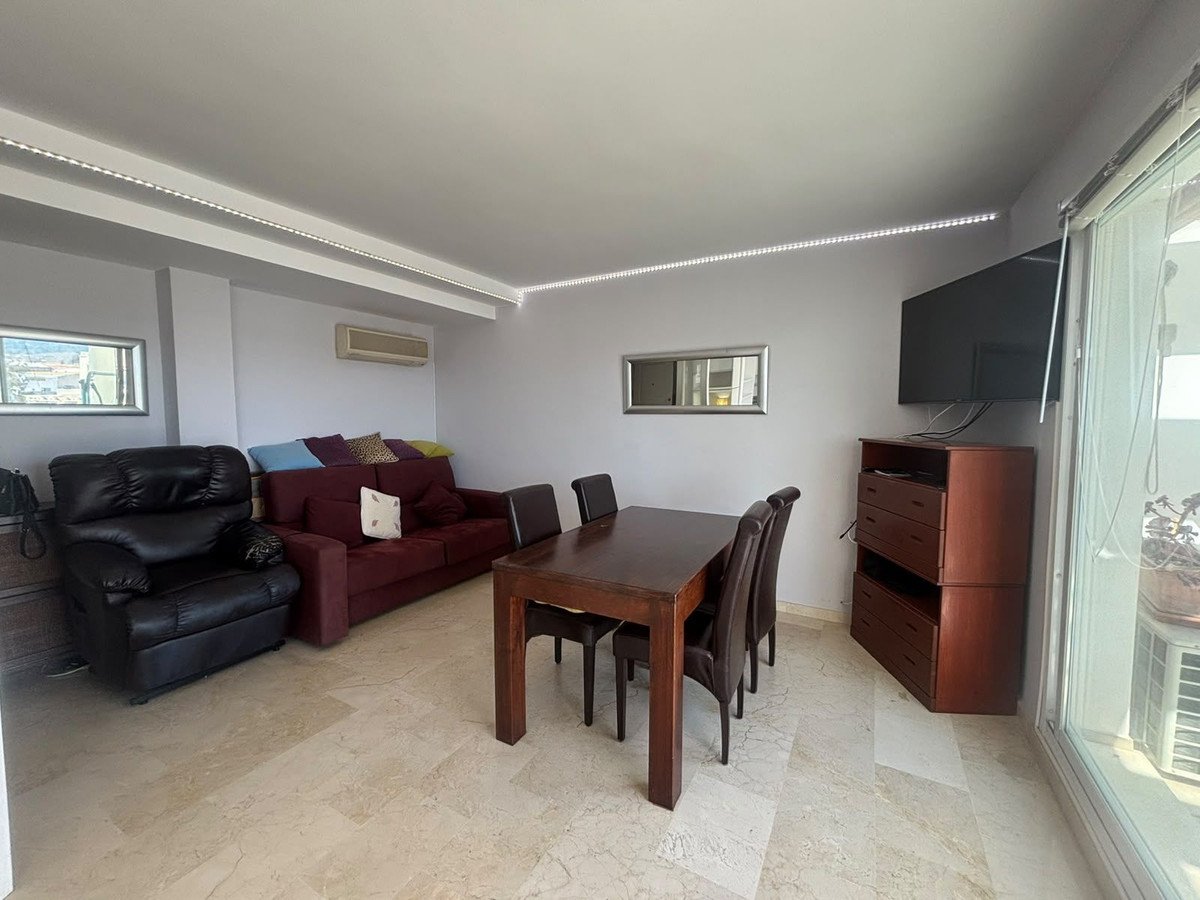 Living and dining area with a sofa, armchair, dining table, and a mounted TV.