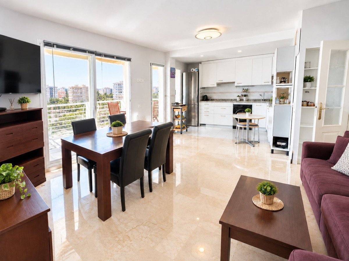 Spacious open-plan living, dining, and kitchen area with a balcony offering city views.