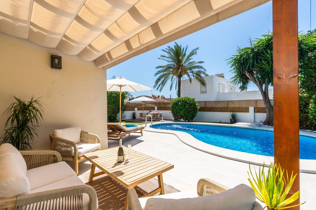 Outdoor patio with a blue swimming pool, lounge chairs, outdoor seating, and a table with champagne.
