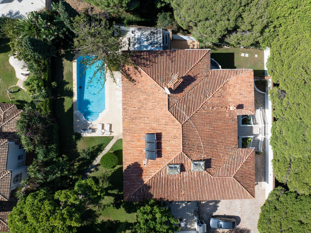 Aerial view of a villa with terracotta roof, swimming pool, and surrounding greenery.